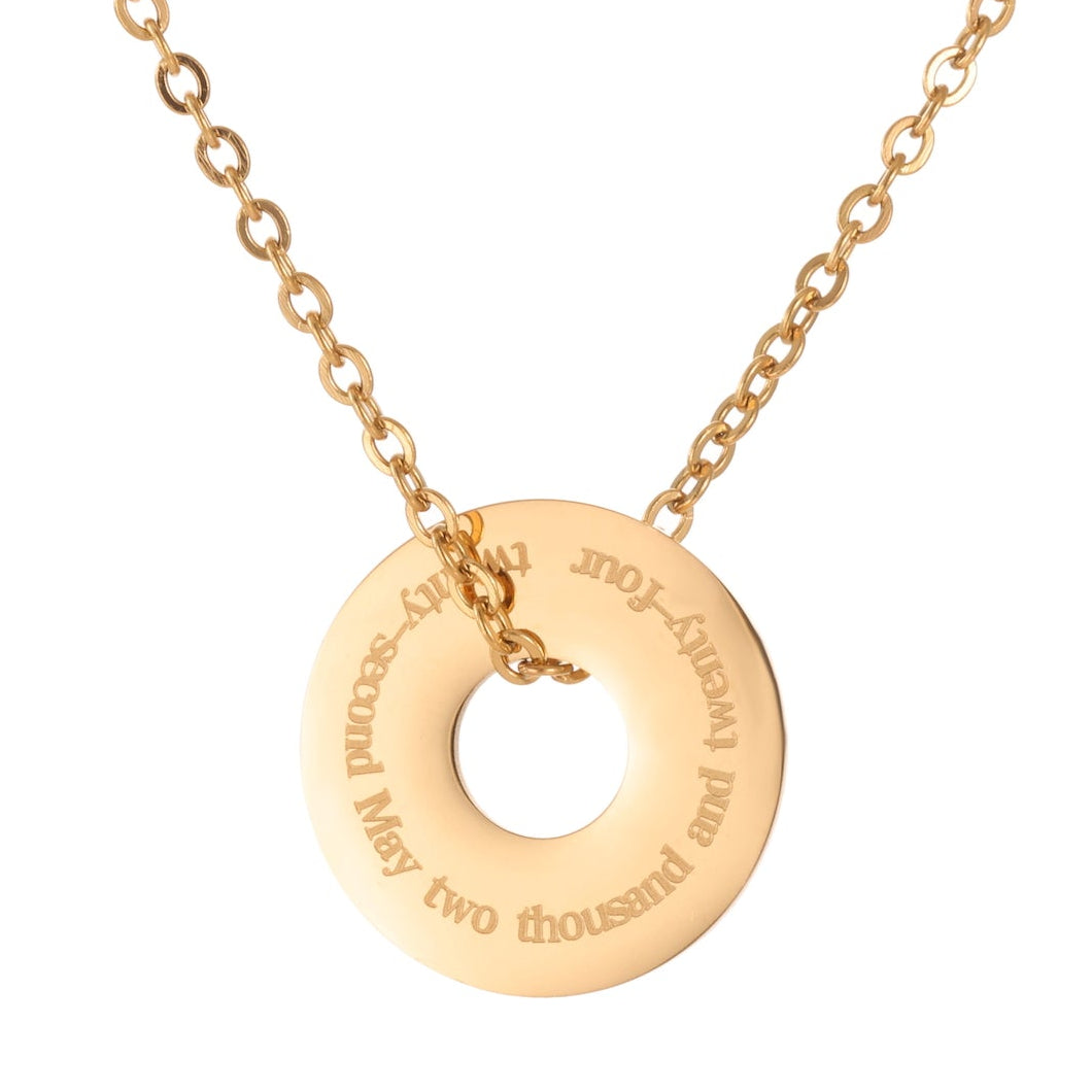 Gold necklace with a round pendant on a white background engraved with a date in full text